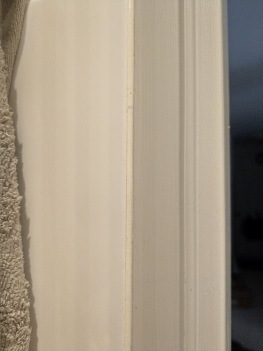 Närbild av en nyligen installerad vit dörrlist mot en vägg.