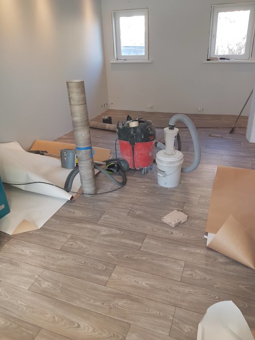 Nylagt trägolv i ett pågående renoveringsprojekt med verktyg och byggmaterial utspridda.