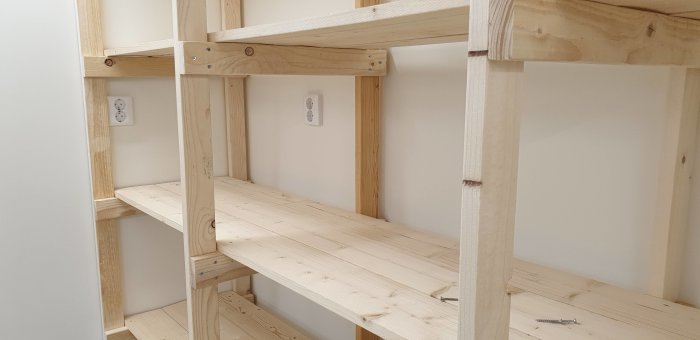 Trähylla byggd med glespanel, behov av förstärkning mellan vågräta träreglar syns.