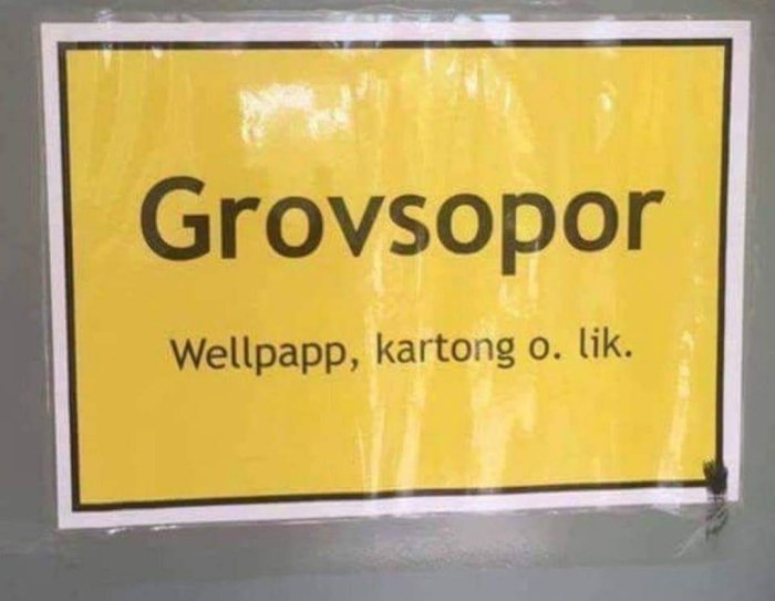 Skylt med texten "Grovsopor" och under "Wellpapp, kartong o. lik." med en fluga i nedre högra hörnet.