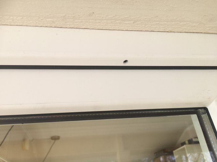 PVC-fönster med ett synligt borrat hål i dess överkant under övre fönsterlist.