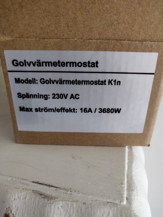 Etikett för golvvärmetermostat modell K1n med specifikationer 230V AC, maxström 16A/3680W på en kartong.