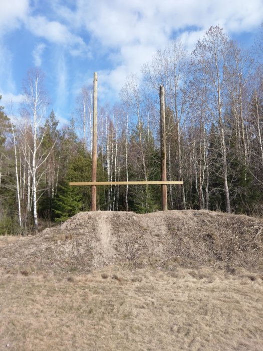 Stommen till ett blivande trähus formad som piratskepp, med vertikala stolpar i en skogsglänta.