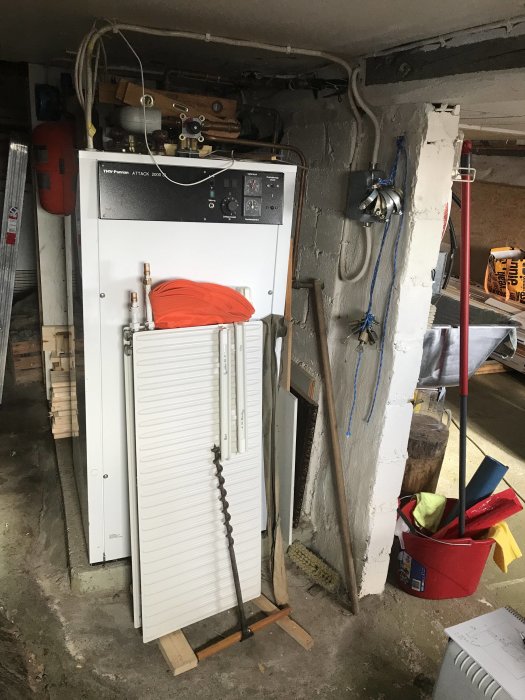 Gammal elpanna i ett rörigt källarutrymme före byte till luft/vatten värmepump.