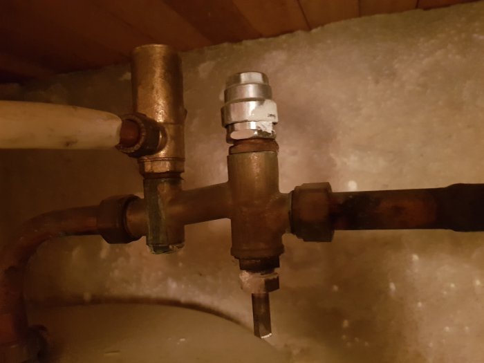 Äldre rörkoppling med säkerhetsventil, inkommande vattenrör till höger och prisolrör till ventilen.
