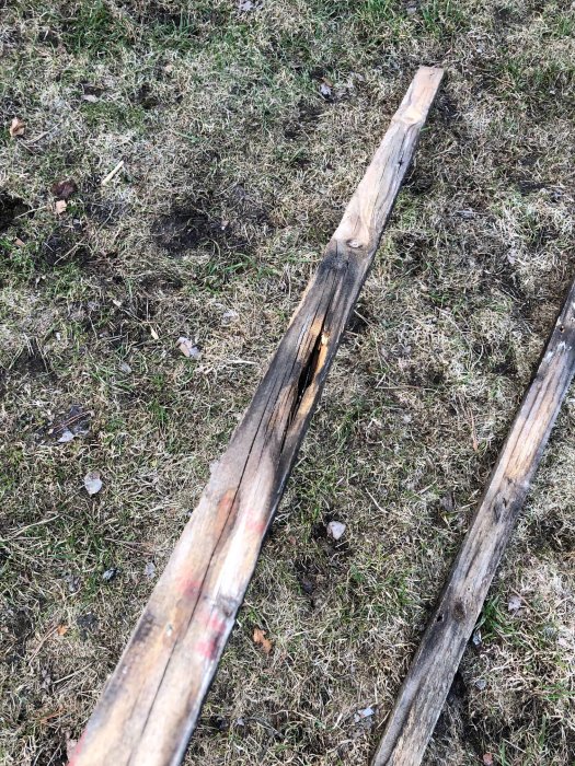 Gammal nockbräda med rötskador som ligger på gräsmark, bytt under takrenovering.