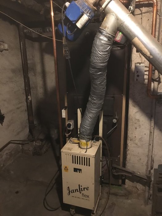 Pelletspanna i källare med synliga rör och isolerade ledningar, Janfire Flex modell.
