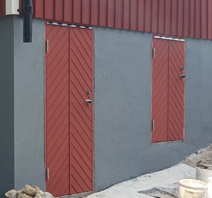 Röda dörrar i en grå vägg, den högra dörren leder till en matkällare och är 140 cm hög.