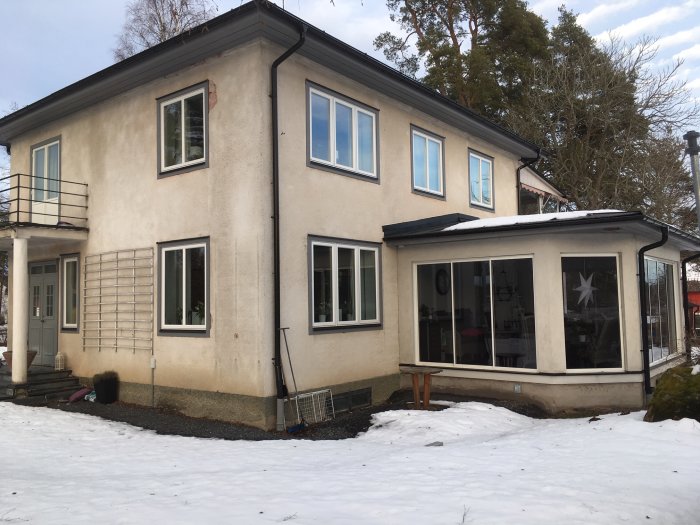 Ett hus från 1936 med putsad fasad omgivet av snö, undersöks för tilläggsisolering och ny puts.