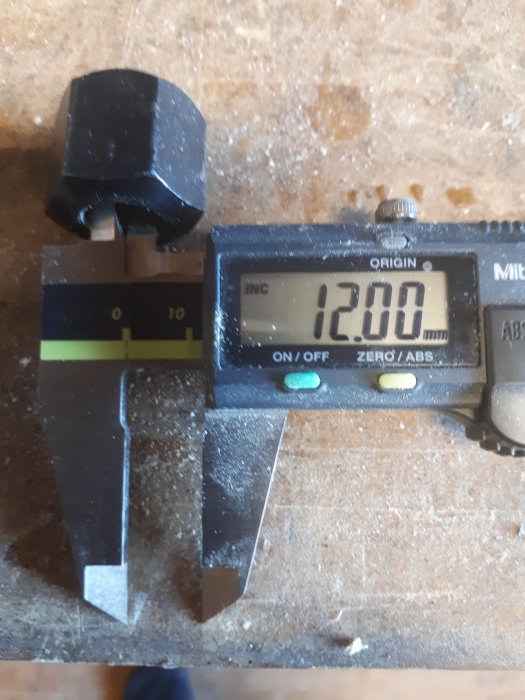 Digital skjutmått som visar ett mätresultat på 12,00 mm på en arbetsyta.