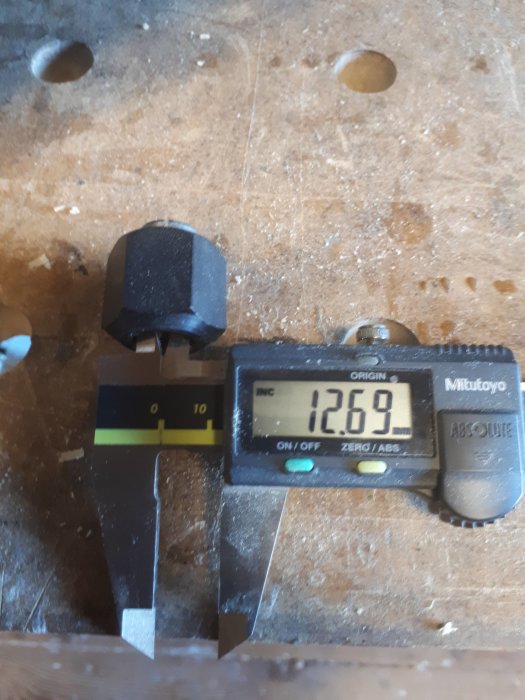 Digital skjutmått från Mitutoyo som visar mätvärde 12,69 mm på en träyta.