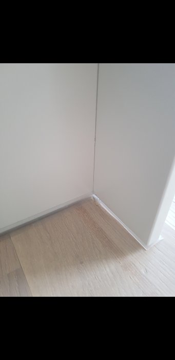 Otillfredsställande hantverksarbete med synlig skada längs skåpets hörn och golv.