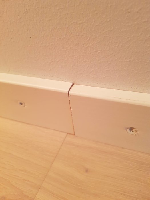 Dåligt monterade vitmålade lister med stora synliga skruvar och övermålad vit färg.