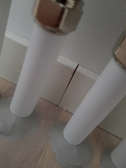 Ojämnt målade rör och slarvigt utförd fogning mot golv och vägg.