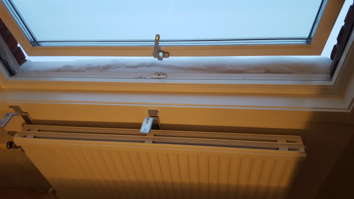 Ett öppet vipp-fönster ovanför en radiator, märkt "FIX Made in Sweden" på undersidan.