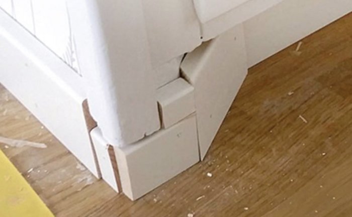 Dåligt passande vitmålade fotlister vid ett hörn där snickeridetaljerna inte möts korrekt.