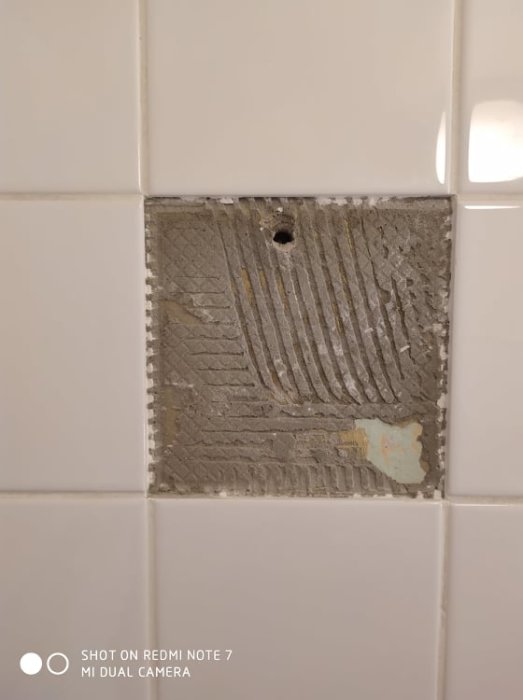Ta bort kakelplatta i dusch med synligt lim, skadat möjligt tätskikt och borrhål.