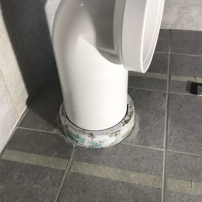 Toalettstol med universalvattenlås ovanpå ett golvmonterat excenterrör.