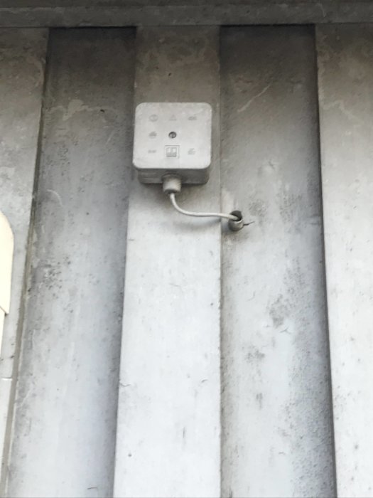 Okänd anordning monterad på vägg med kabel och anslutningar, möjlig givare.