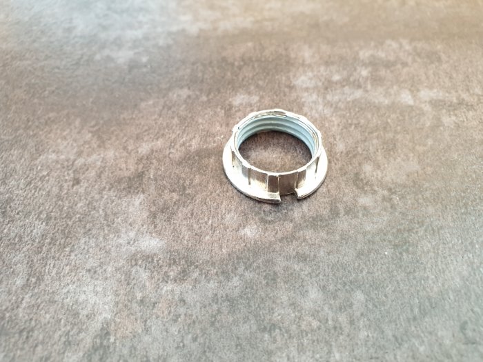 Skadad skärmring i krom för G9 sockel på en grå yta, använd för att fästa lampskärm.