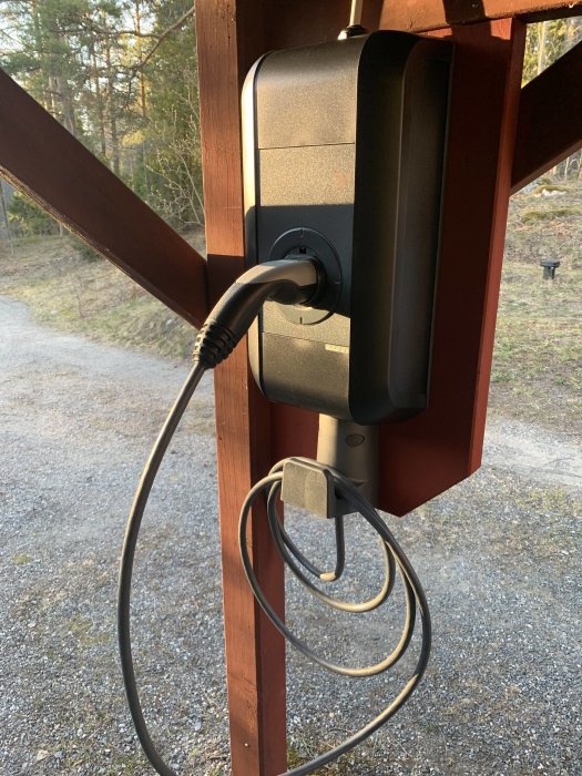 Nyinstallerad laddstation för elbil monterad på en trästolpe med kabel och kontakt.