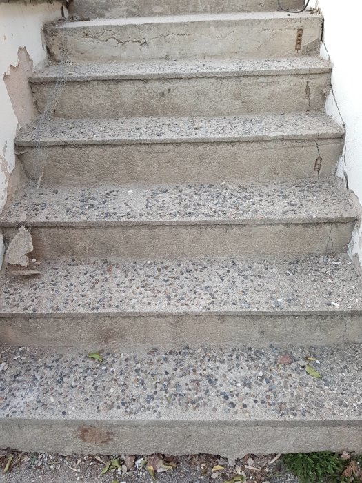 Slitna betongtrappsteg med sprickor och fläckar, i behov av renovering.