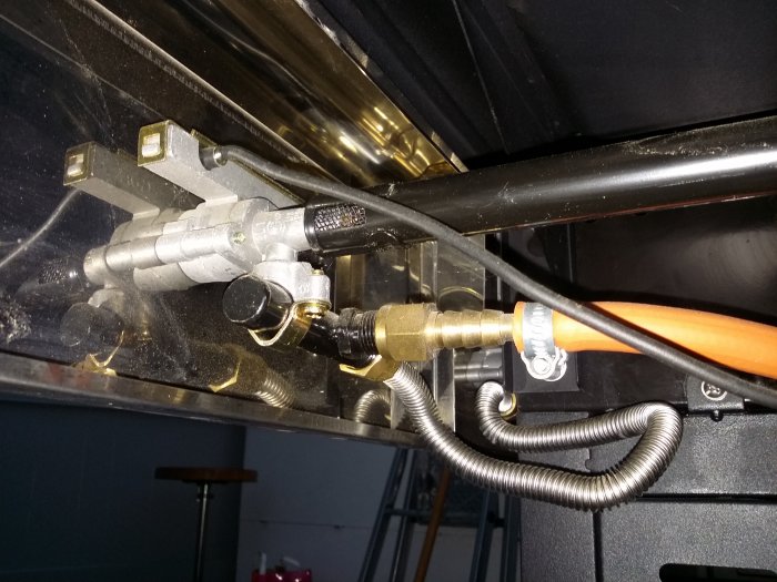 Mekanisk koppling på en Triton med ett löst sittande rör nära reglage och en ansluten orange gasolslang.