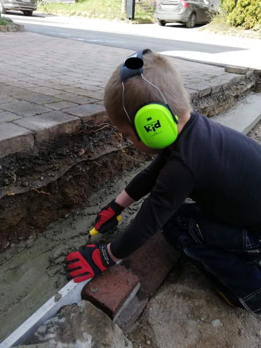 Barn hjälper till med betongarbete för stödmur vid blivande parkeringsplats.