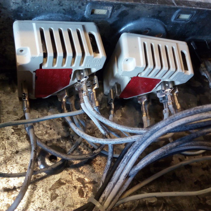 Bild på insidan av en spishäll med brända säkringsmottagare och gamla elektriska kablar, tecken på eldsvåda.