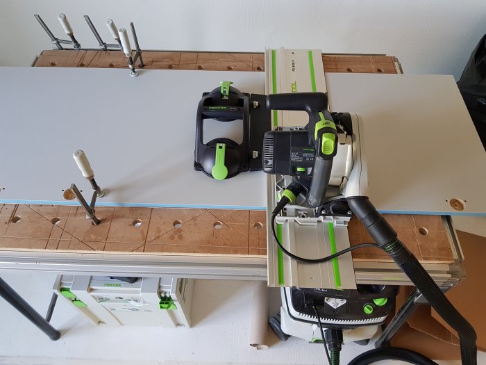 Garderobsbygge med nedkortad garderobsdörr fastklämd på arbetsbord, omgiven av Festool-verktyg och Gecko sugkopp.