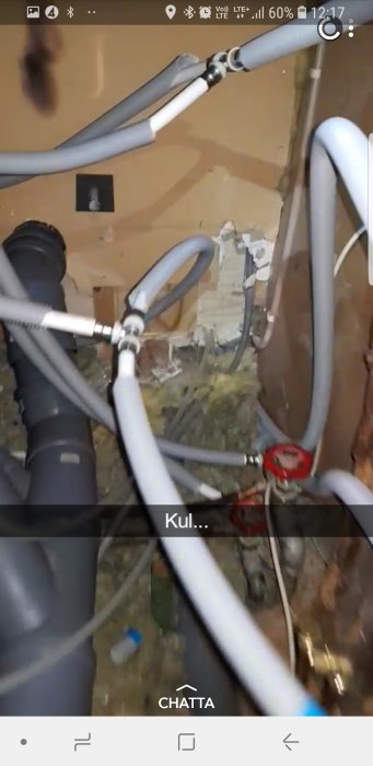 Rördragning på kattvind med hopkopplade vattenledningar och en röd ventil.