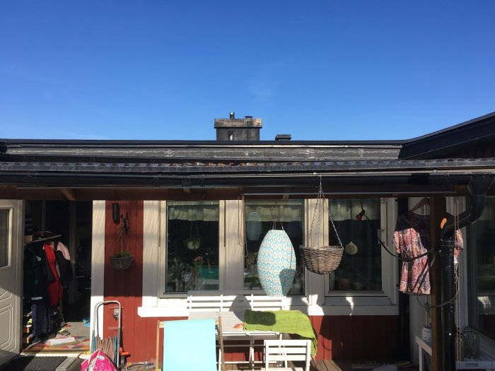 Altantak med lätt svacka i mitten över en innergård, med två lodräta reglar och horisontella plankor.