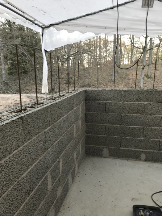 Byggprocess av pool med isolering och installationer för inlopp och belysning, under ett tält.