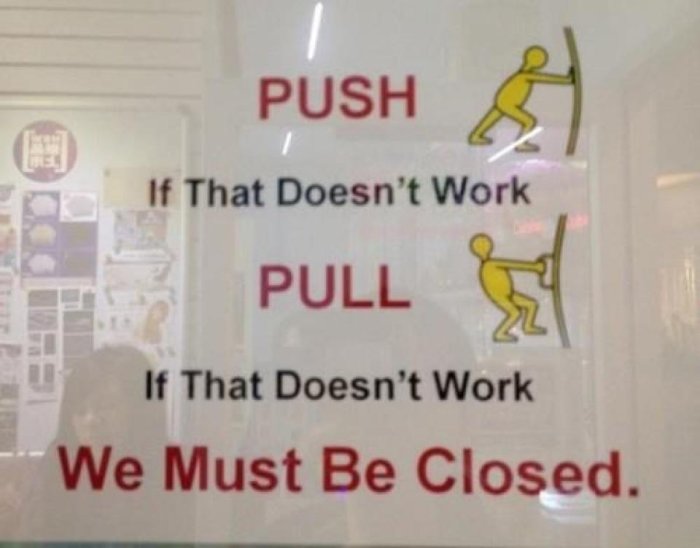 Humoristisk skylt med instruktioner "PUSH" och "PULL", samt "We Must Be Closed" om inget fungerar.