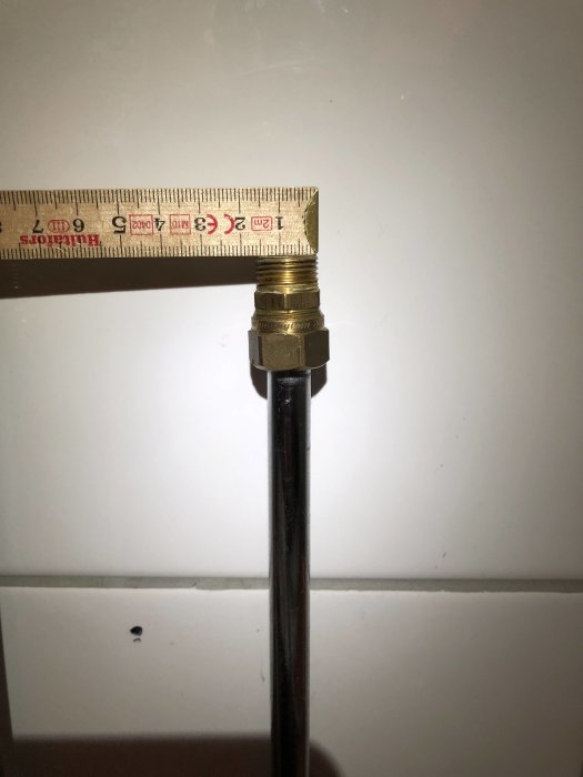 Kromat rör mätt med tumstock, klämringkoppling synlig vid anslutningen.