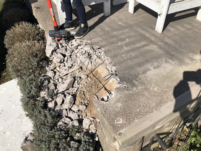 Rivningsarbete av betongplatta på uteplats med verktyg och krossad betong synlig.