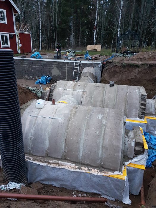 Konstruktionsfas av vinkällare med halverade betongrör för tak och isolermaterial runt.