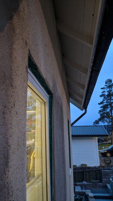 Husfasad i skymningen med fönster och takdetaljer där man kan tänka sig att borra för belysningskablar.