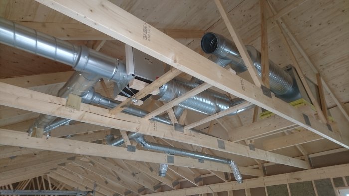 Ventilationsrör installerade mellan träreglar på en byggarbetsplats.