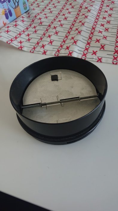 Kolfilterfläktens anslutningsadapter på ett vitt bord, ca 117 mm, mot mönstrad bakgrund.