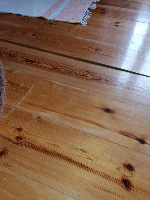 Trägolv i stuga med en uppstickande bräda som skapar en 2 cm kant.