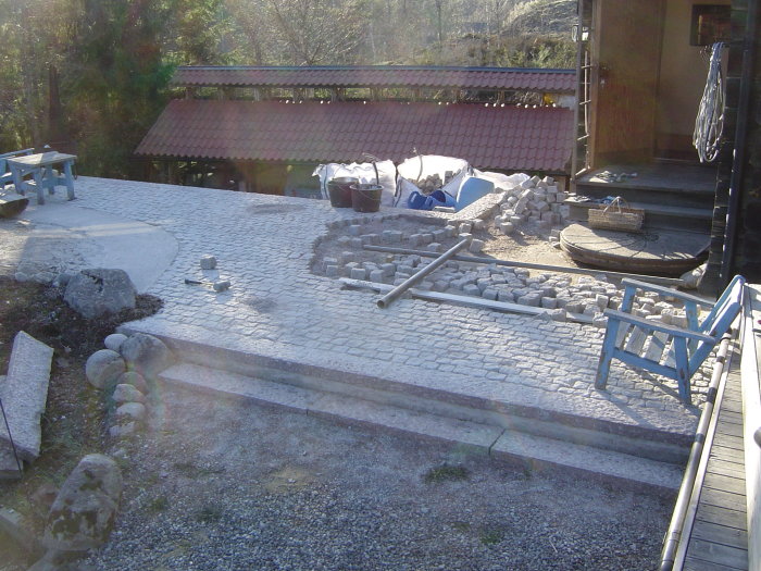 Ongoing garden renovation with cobblestone pavement and construction materials.