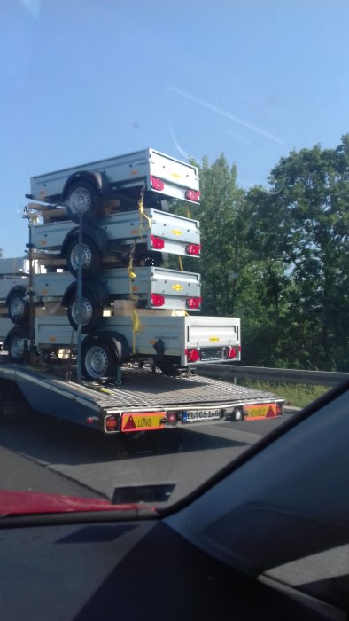 Släpvagnar i olika storlekar staplade på en transport på autobahn.