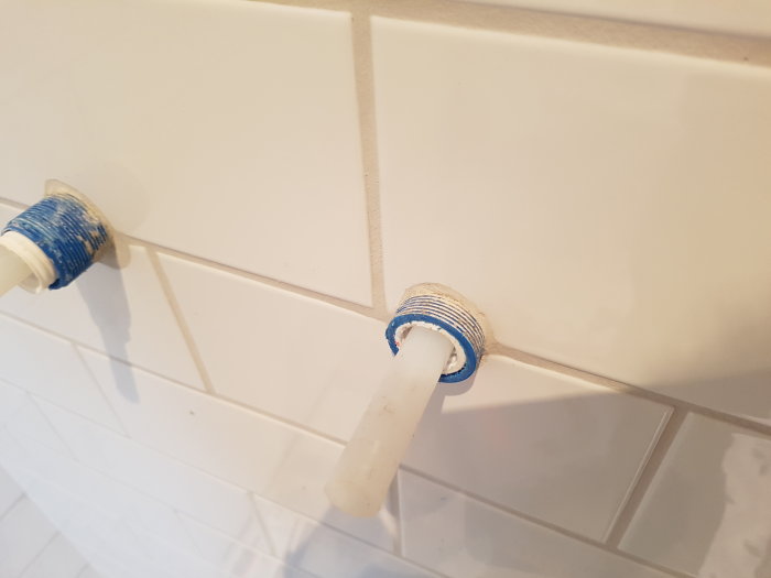 Handgjord skyddsrör i stål och sammansatt masonitskiva monterad på badrumsvägg.