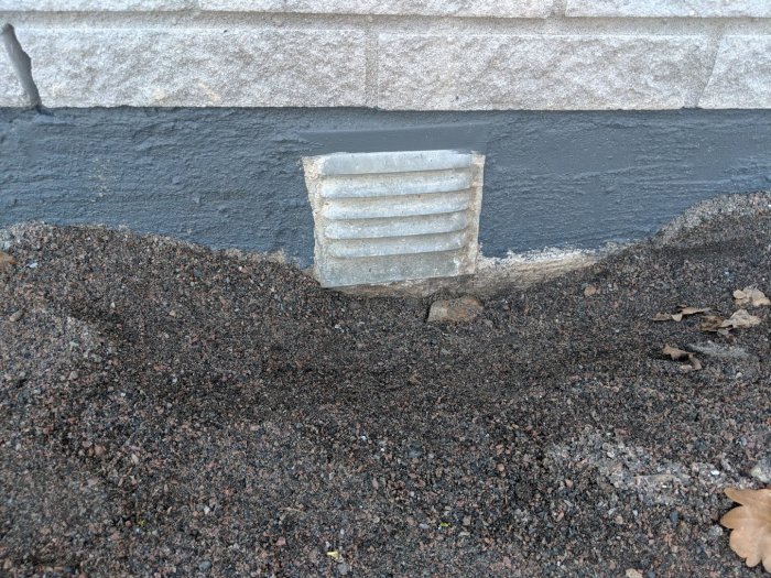 Ventilationsblock på husgrund med grus runtomkring och plats för marksten.