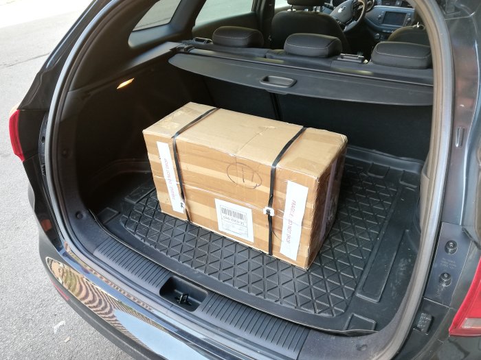Stor kartong i bagageutrymmet på en bil, redo för transport i samband med byggprojekt.