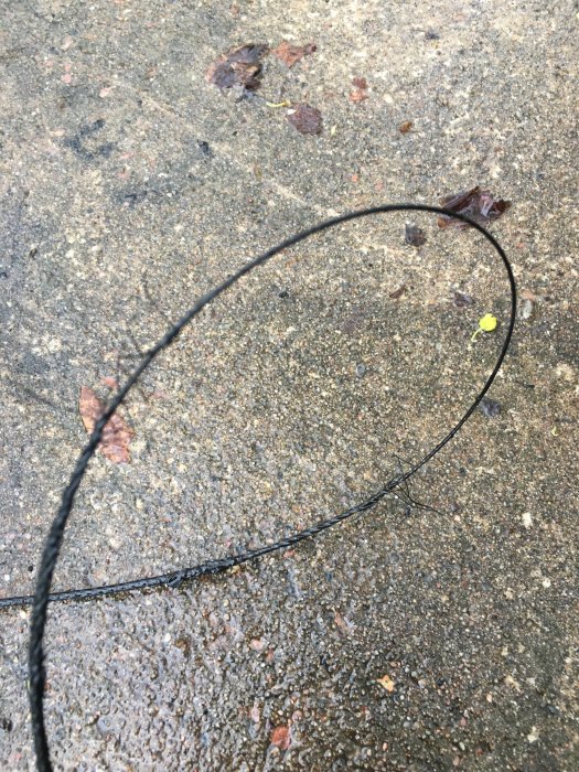 Nött och skadad vajer på betongunderlag med tecken på slitage och potentiell mettalltrådsbrott.