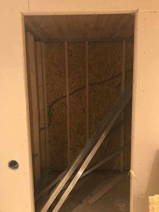 Renoveringsprojekt av källare med synliga 45-reglar, OSB-skivor och gips i förberedelse för bastuinstallation.