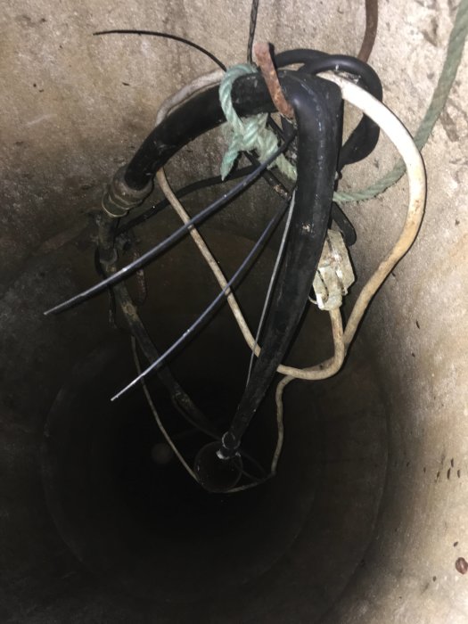 Bild av en brunnsöppning med rör och kablar, vilket visar problemet med hydroforens långsamma påfyllning.