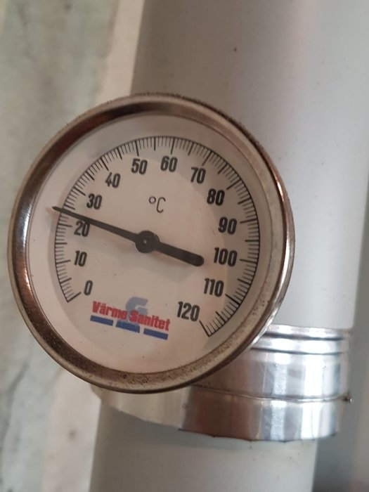 Termometer på ett rör som visar cirka 40 grader Celsius, märkt "Värma Sanitet".